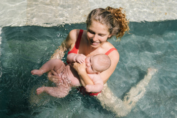 Mutter schwimmt mit ihrem Baby zusammen im Schwimmbecken.
