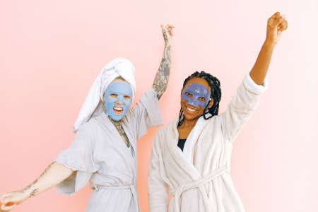 Zwei Frauen im Bademantel und mit Gesichtsmaske.