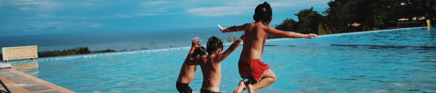 Kinder springen in ein Schwimmbecken – das klare Wasser wurde mit Flockungsmittel für den Pool behandelt