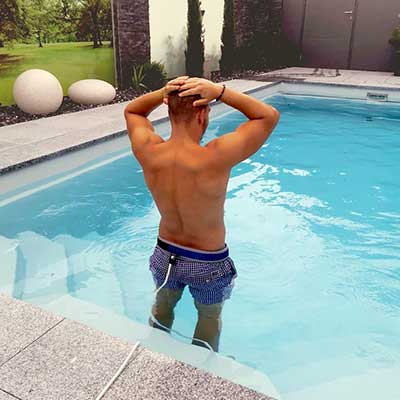 Ein Mann steht im Pool – er trainiert mit einer Gegenschwimmanlage
